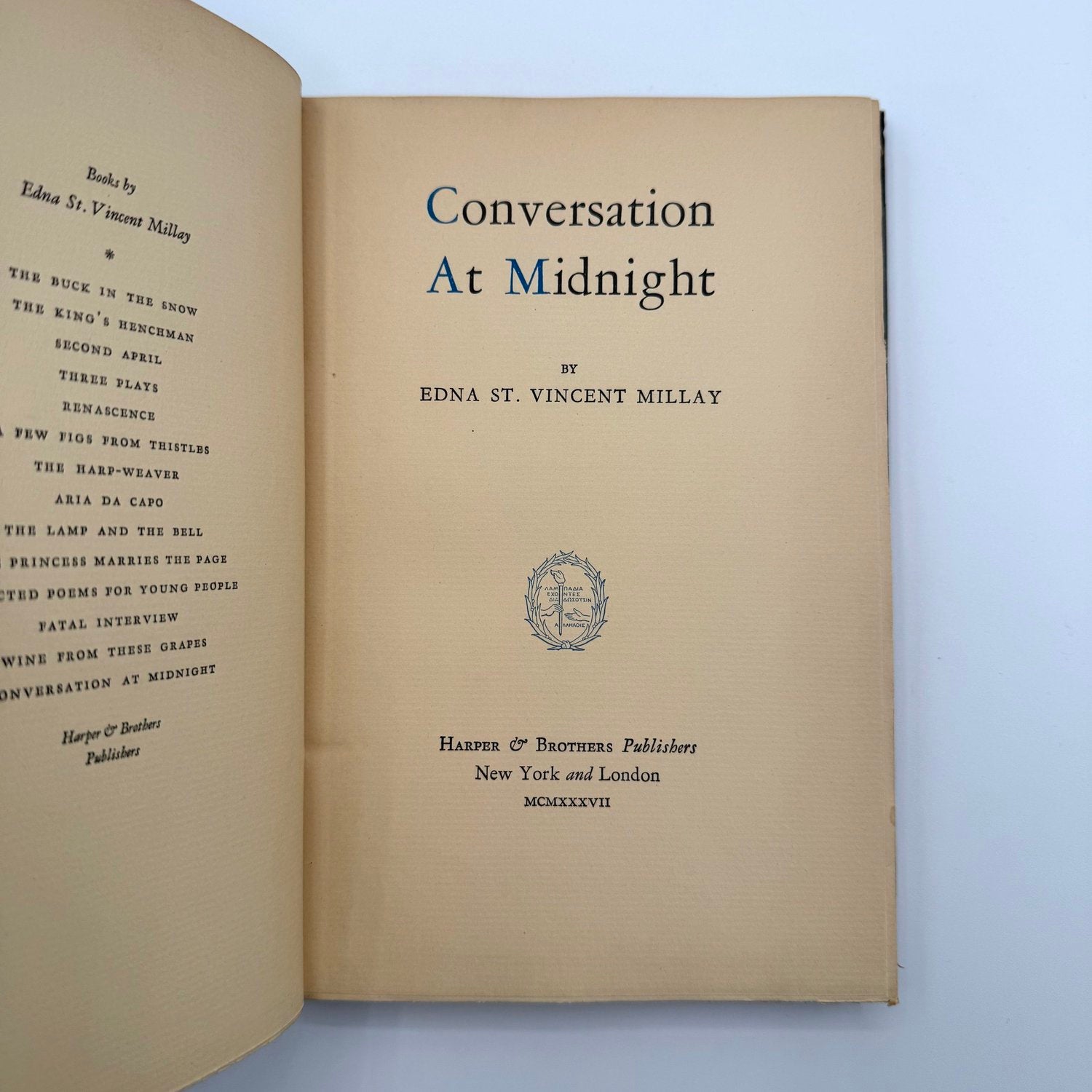 Open book with title page of 'Conversation At Midnight' by Edna St. Vincent Millay on a light blue background