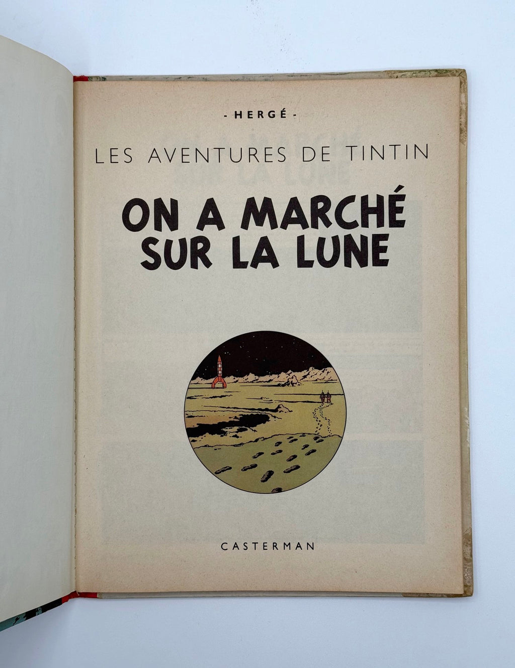 Open book with Tintin cover featuring text and illustration of moon landing.