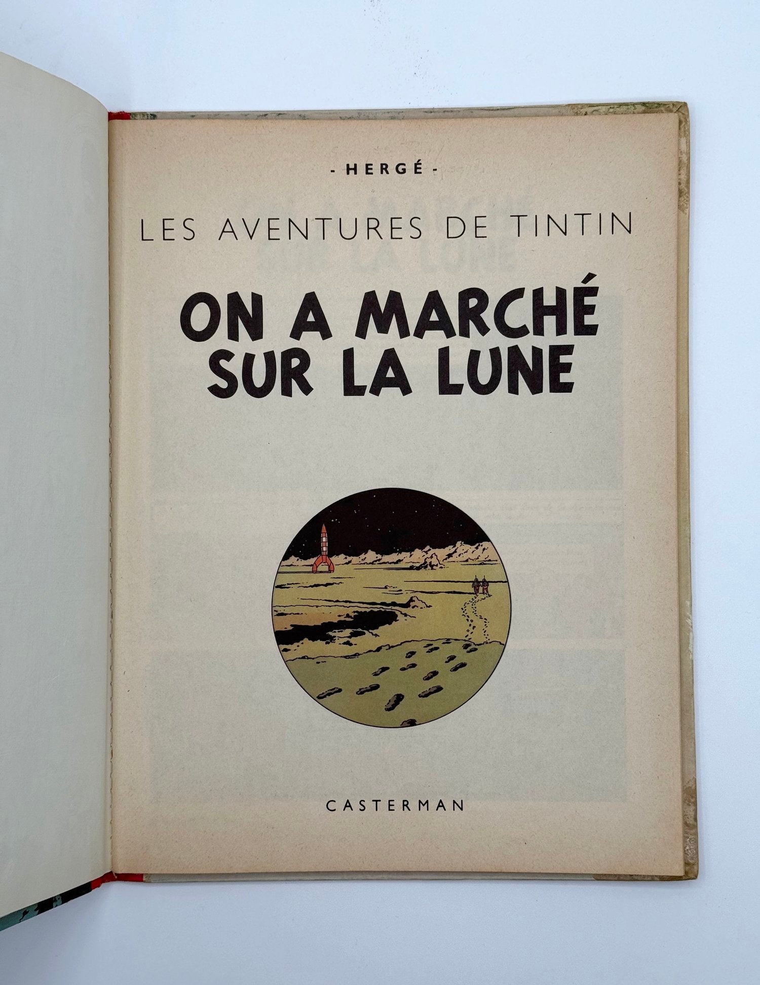 Open book with Tintin cover featuring text and illustration of moon landing.