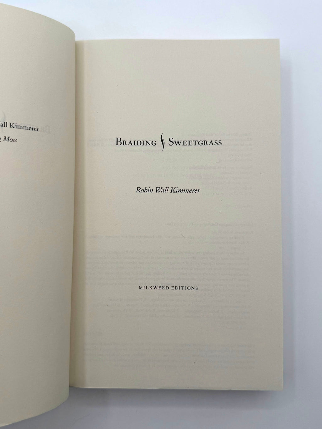 Open book with 'Braiding Sweetgrass' by Robin Wall Kimmerer on a white background