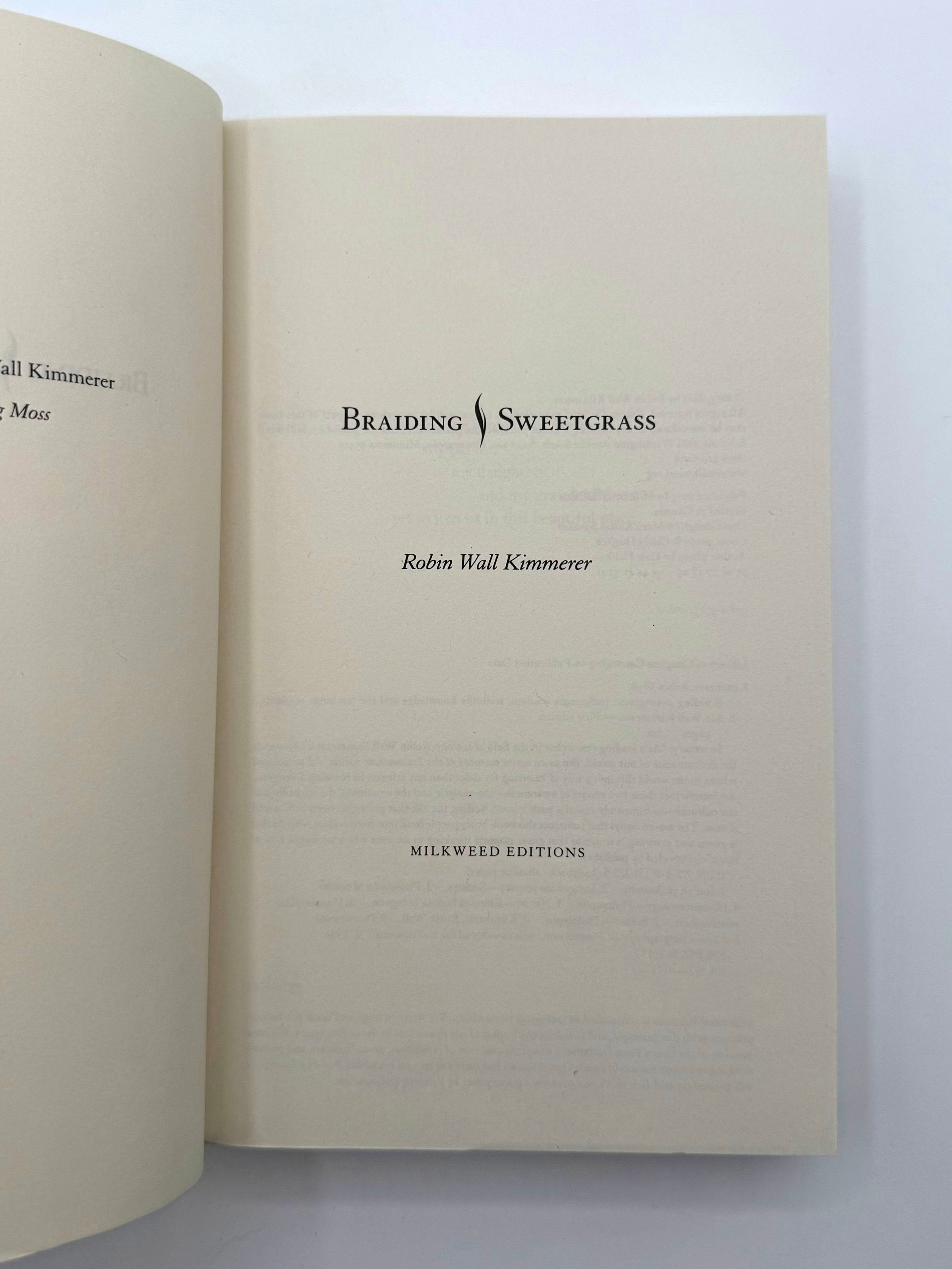 Open book with 'Braiding Sweetgrass' by Robin Wall Kimmerer on a white background