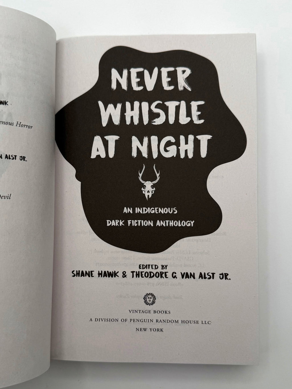 Book open to a page with 'Never Whistle at Night' title and cover design.