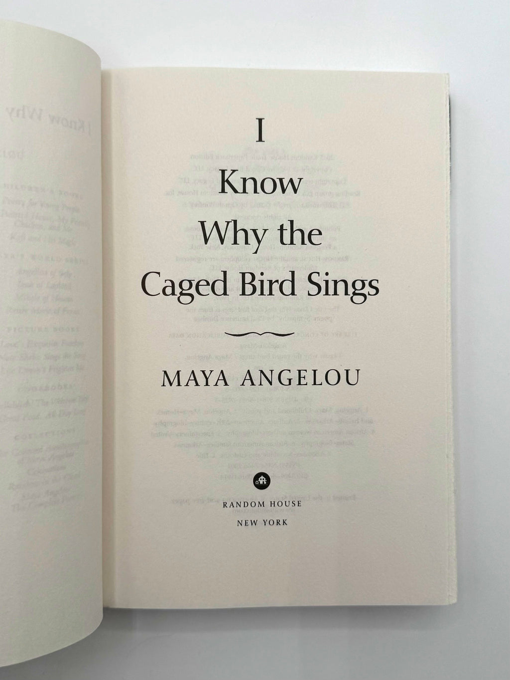 Open book with 'I Know Why the Caged Bird Sings' by Maya Angelou on a white background