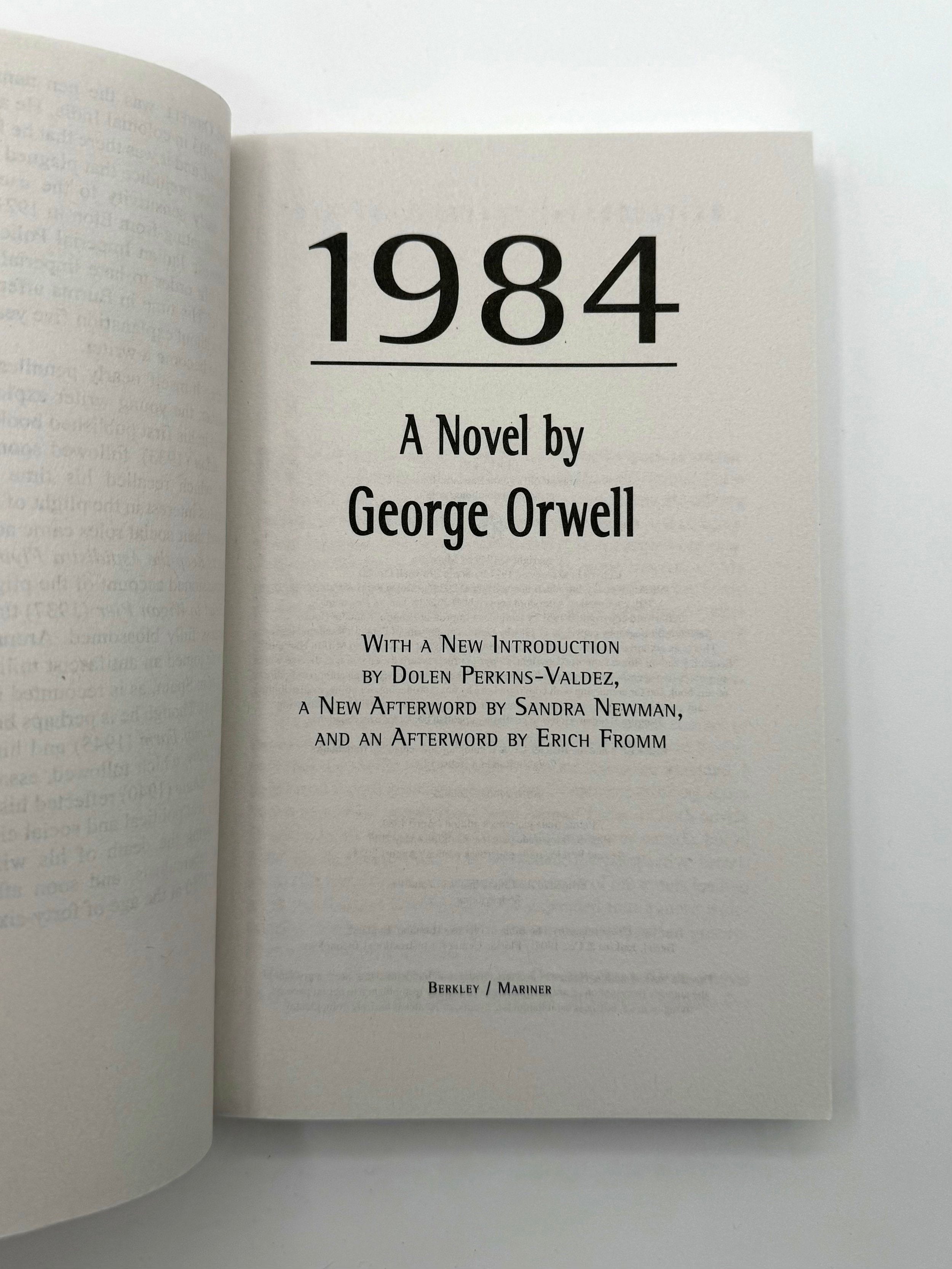 Open book displaying the title '1984' by George Orwell on a white background