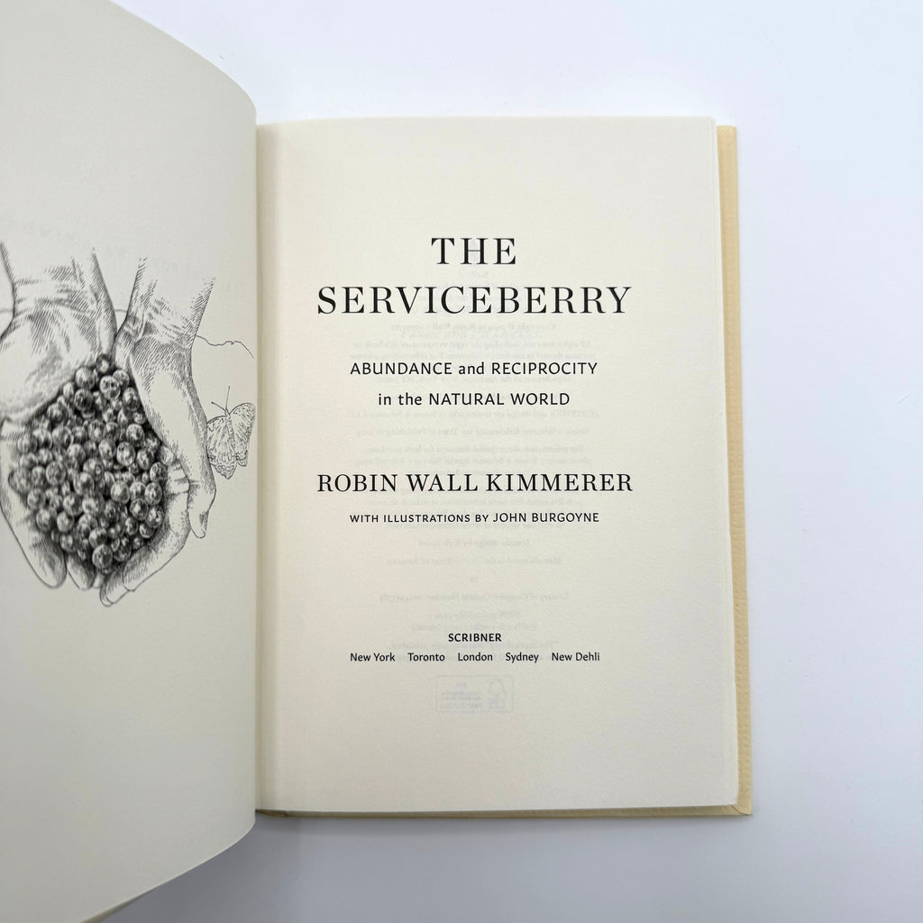Open book titled 'The Serviceberry' by Robin Wall Kimmerer on a white background