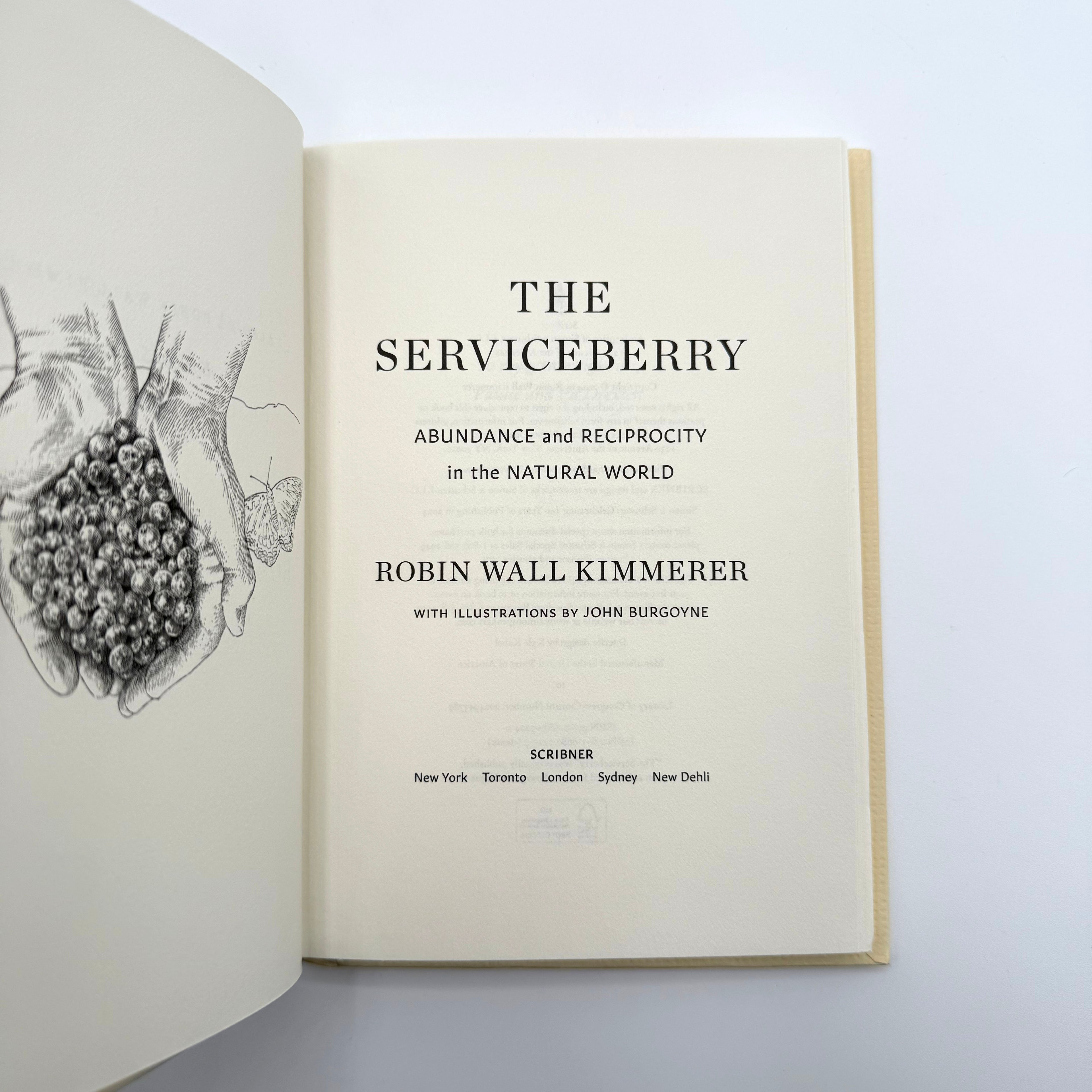 Open book titled 'The Serviceberry' by Robin Wall Kimmerer on a white background