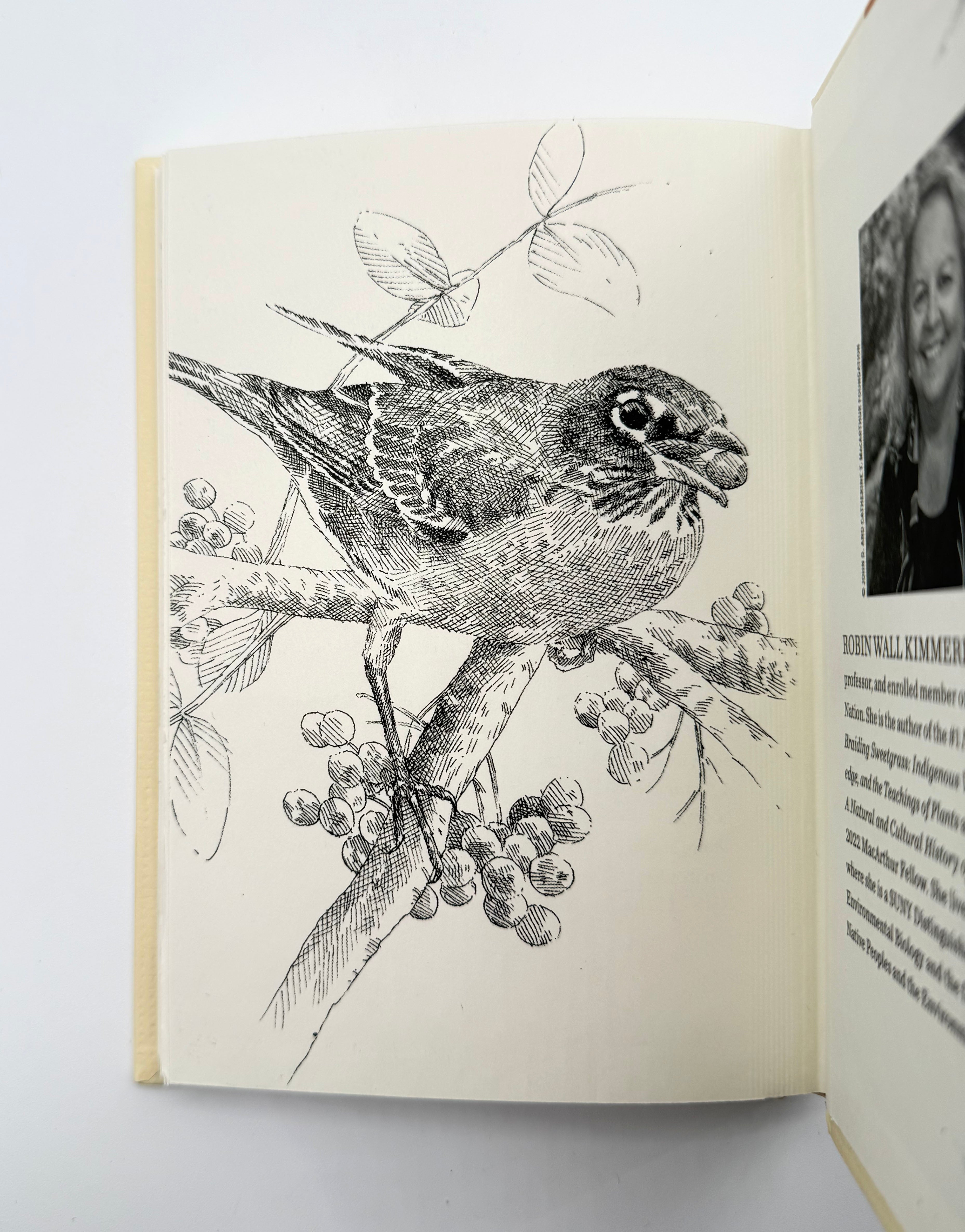 Open book with a black and white illustration of a bird on a branch and a photo of a person on the right page.