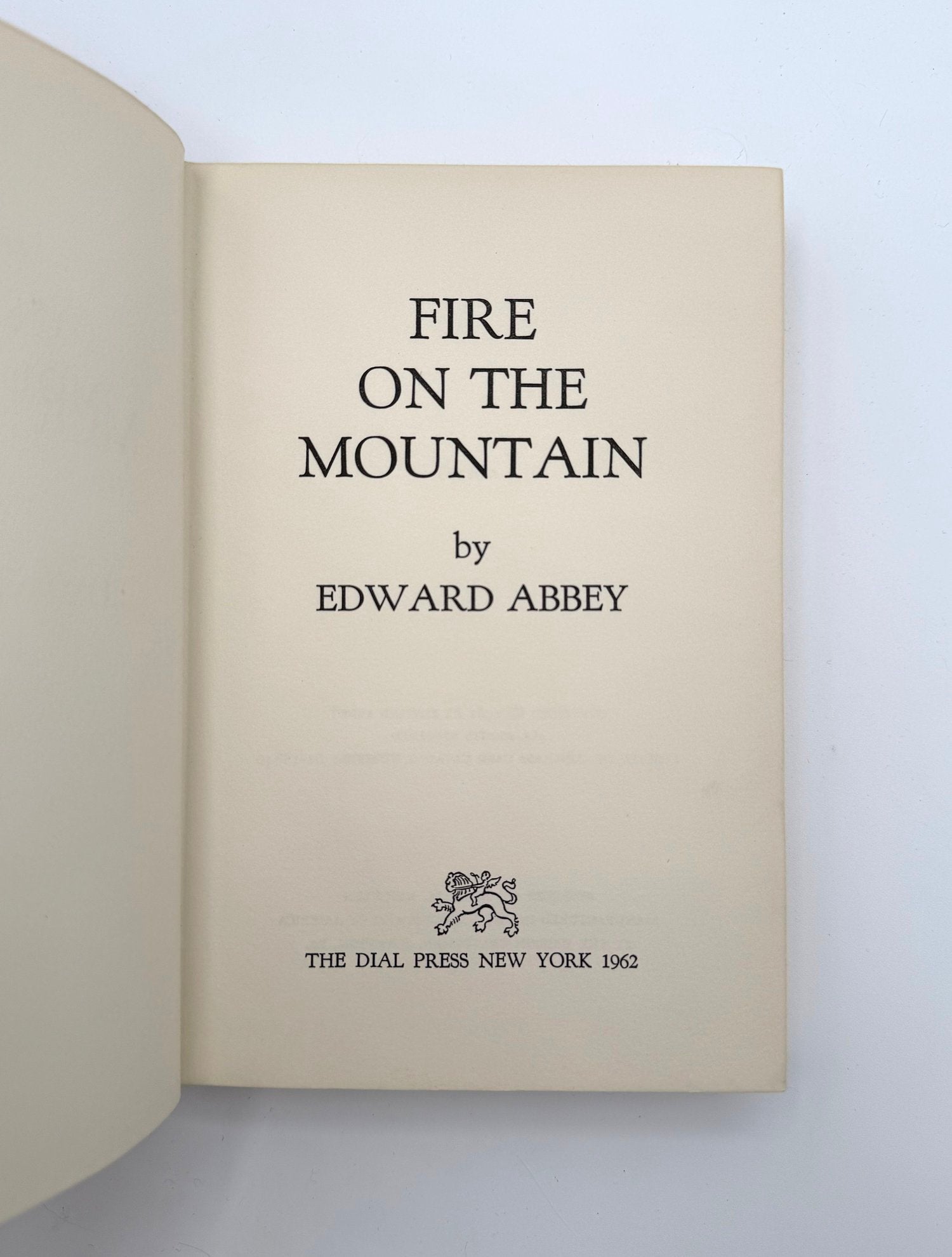 Book titled 'Fire on the Mountain' by Edward Abbey with a visible logo on a light background