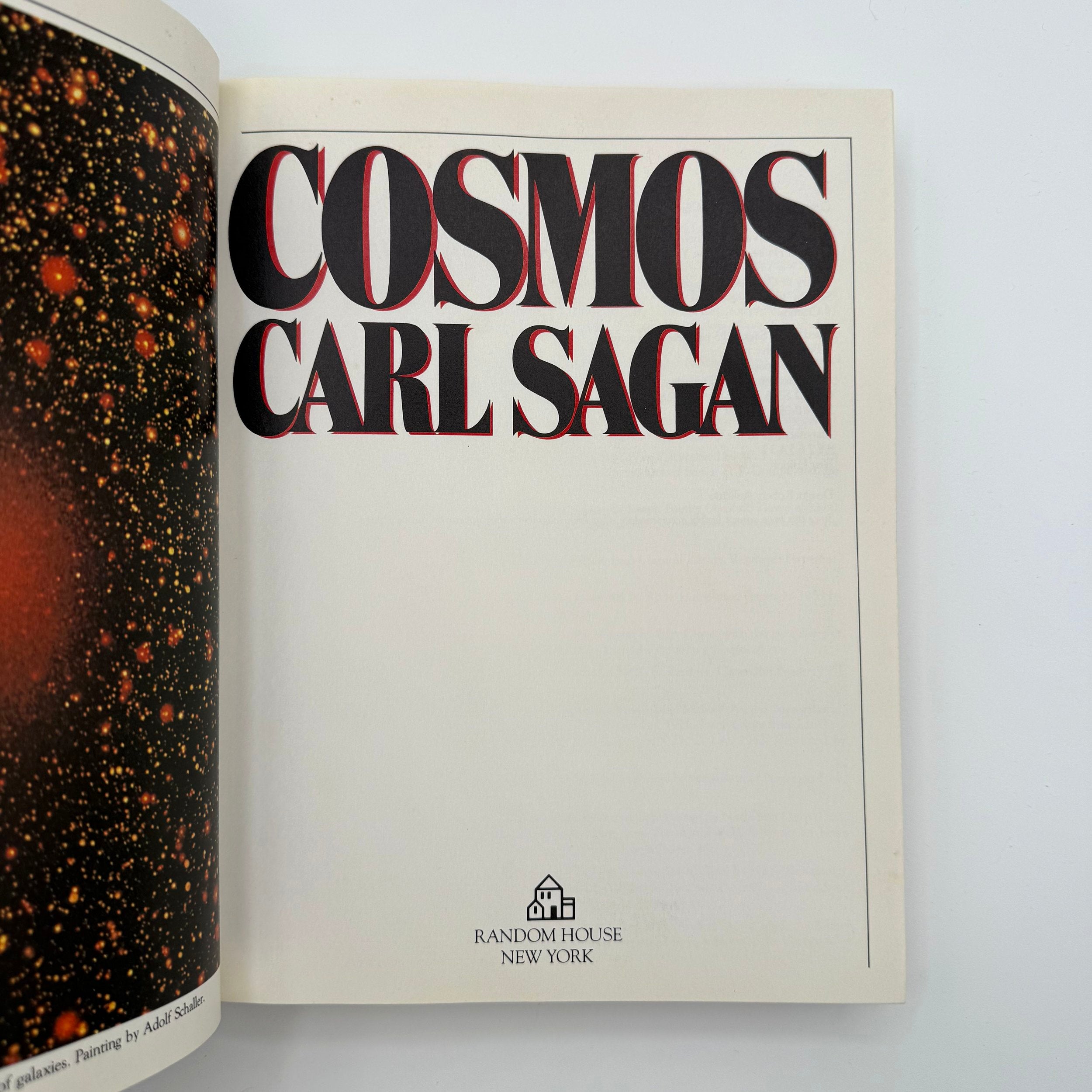 Open book showing the title 'Cosmos' by Carl Sagan with a space-themed cover.