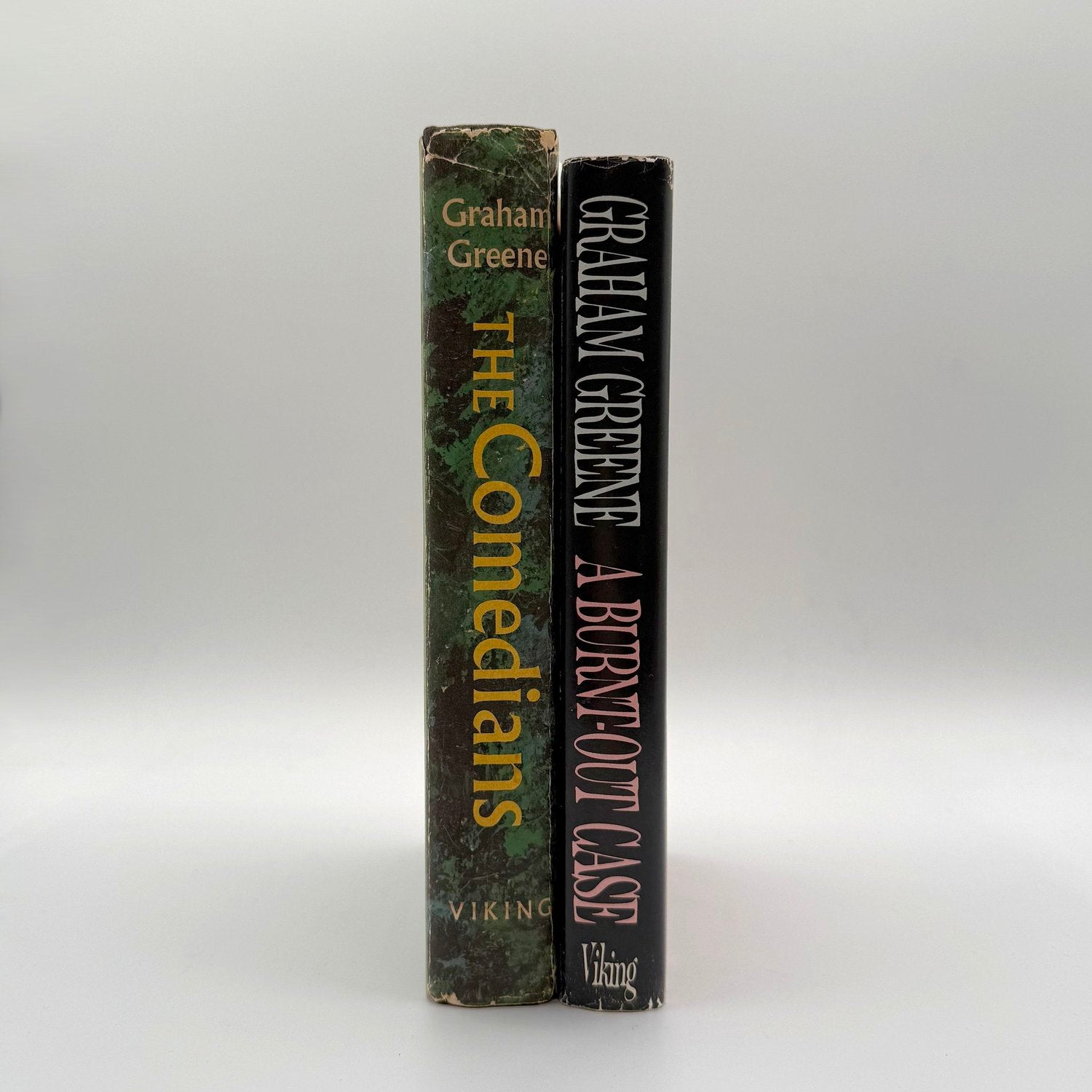 Two books by Graham Greene titled 'The Comedians' and 'A Burnt-Out Case' on a white background.