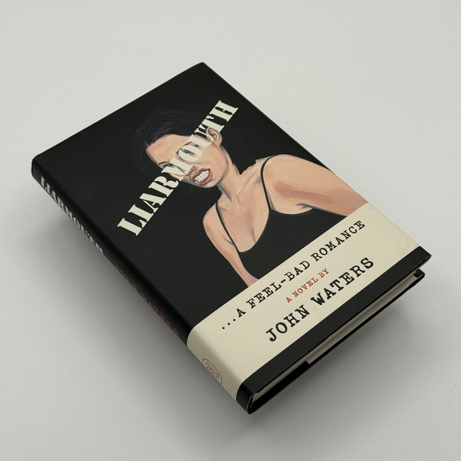 Book titled 'Liarmouth: A Feel-Bad Romance' by John Waters on a light gray background