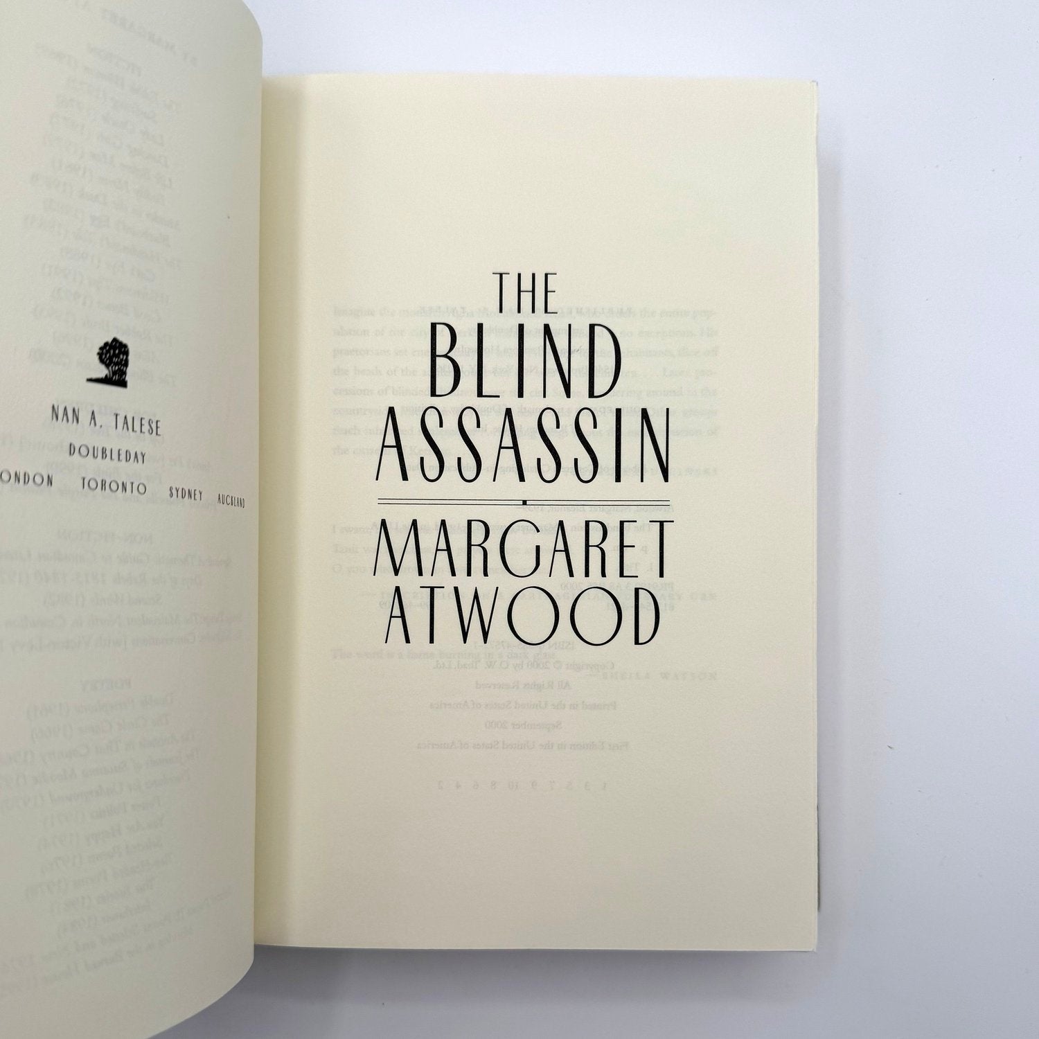 Open book with 'The Blind Assassin' by Margaret Atwood on a white background