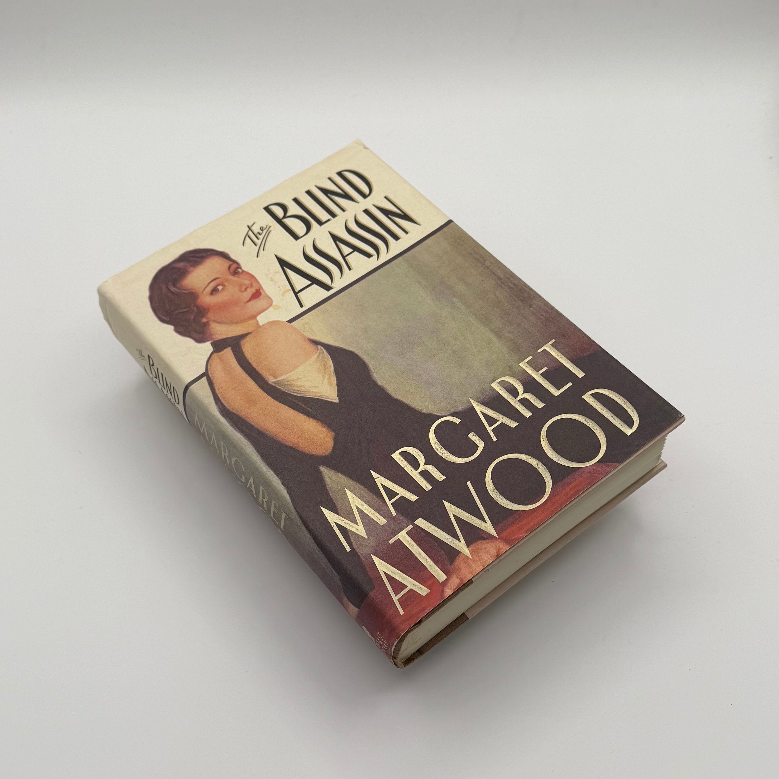 Book titled 'Blind Assassin' by Margaret Atwood on a light gray background