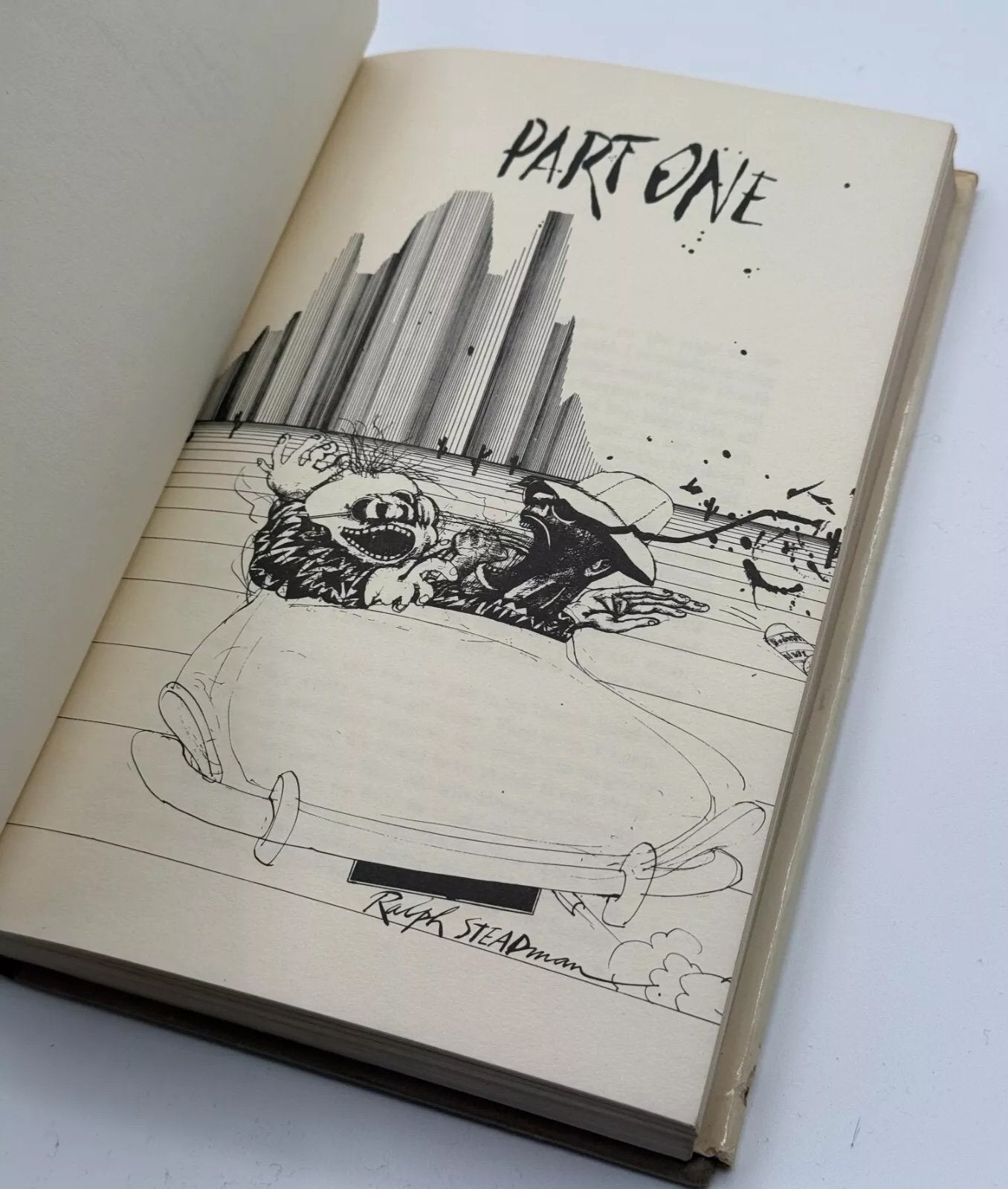 Open book with black and white illustration of a cityscape and skull, titled 'Part One'.