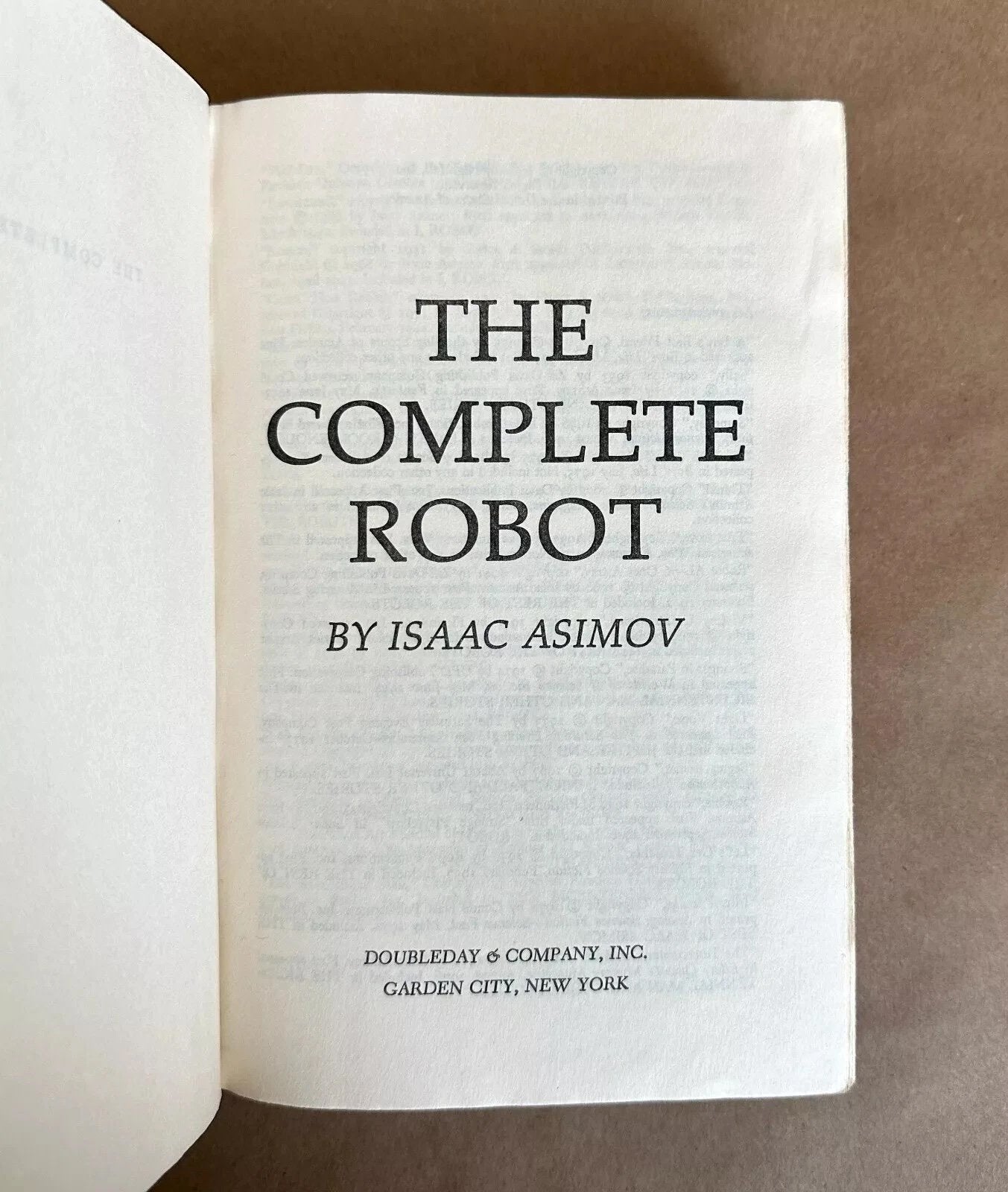 Book titled 'The Complete Robot' by Isaac Asimov on a brown background
