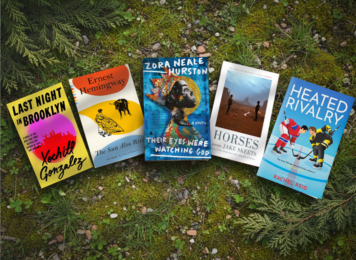 Five books arranged side by side on a bed of green moss and pine needles outdoors. The books are: 'Last Night in Brooklyn' by Yochi Gonzales, 'The Sun, the Altar Road' by Ernest Hemingway, 'Their Eyes Were Watching God' by Zora Neale Hurston, 'Horses' by Jake Sacks, and 'Heated Rivalry' by Rachel Weid.